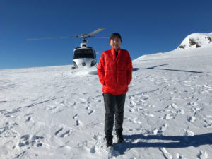 Mary on a glacier with helicopter behind her