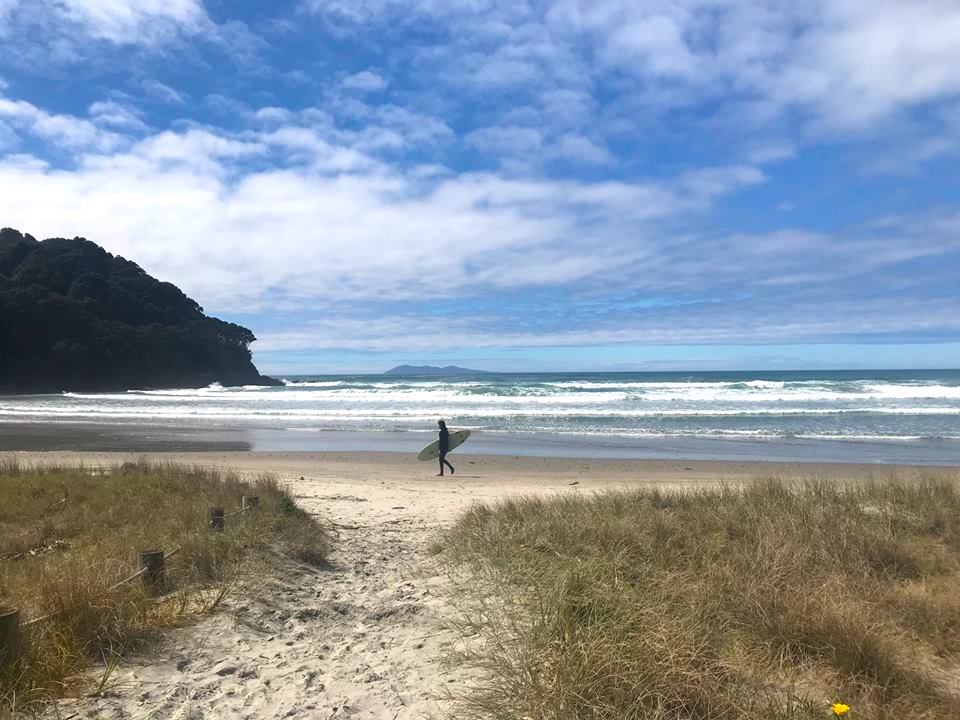 Lone surfer walking along Waihi Beach